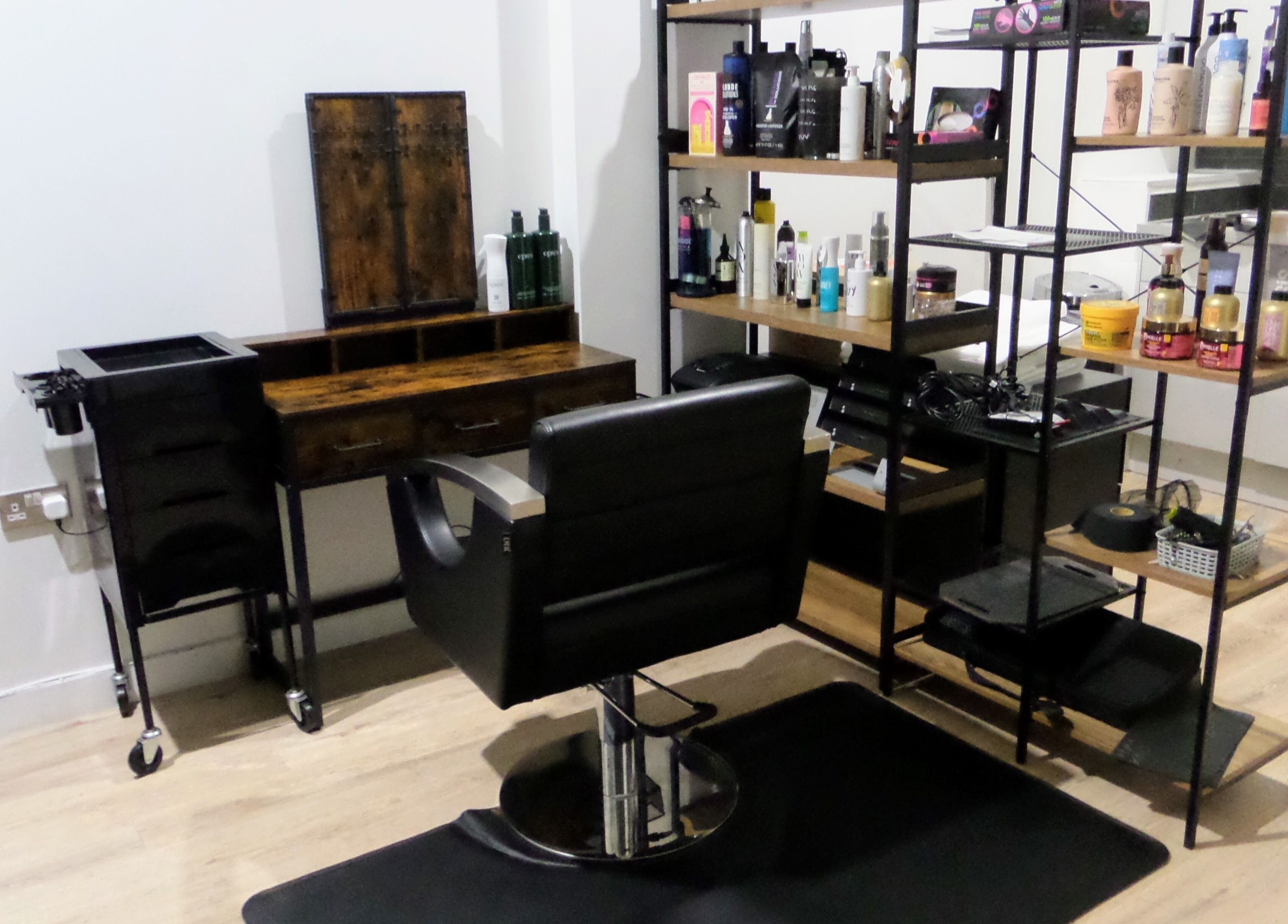 Elegant hair styling station at Zateesha Barbour, London, England, GB, featuring sleek chair and product shelves.