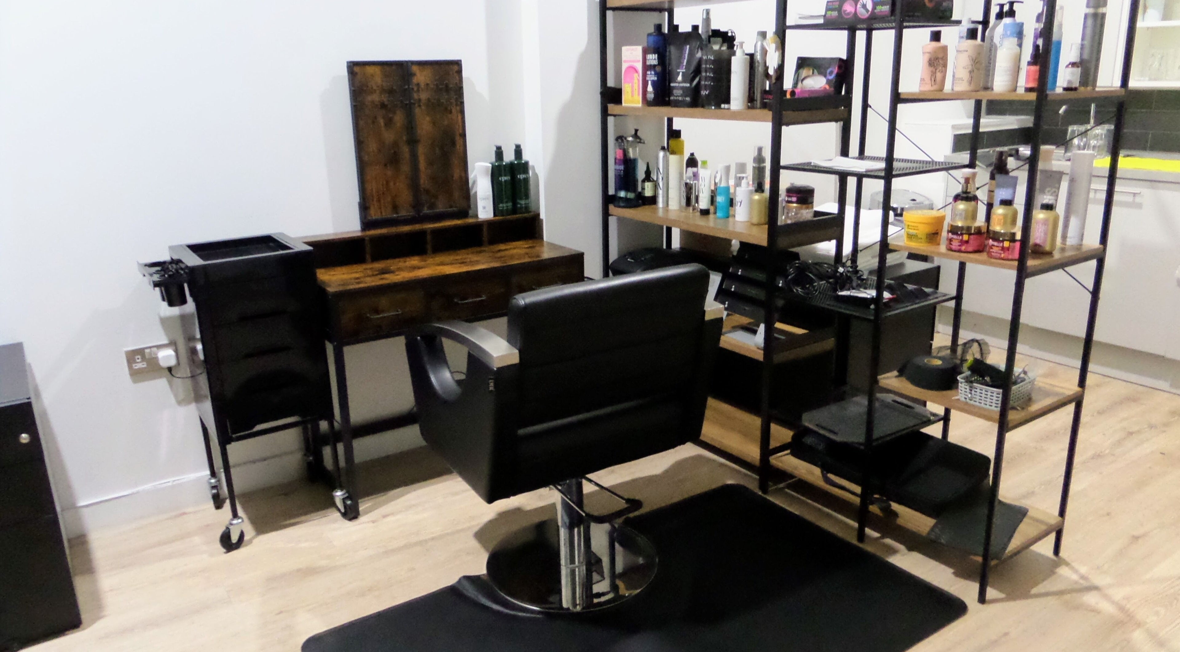 Elegant hair styling station at Zateesha Barbour, London, England, GB, featuring sleek chair and product shelves.