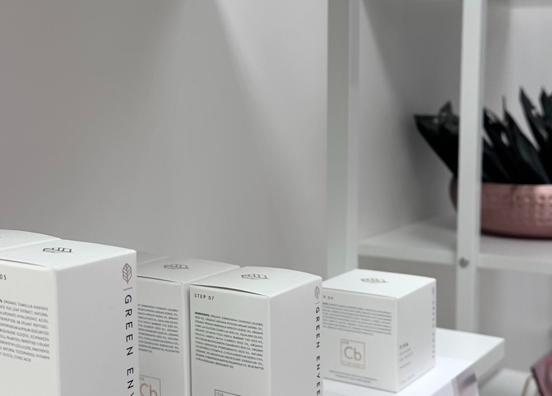 Beauty products on white shelves at Pretty Hurts, Leduc, Alberta, CA, showcasing a serene wellness ambiance.