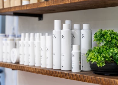 Emava, Solihull, England: Elegant display of beauty products on wooden shelves beside lush greenery.