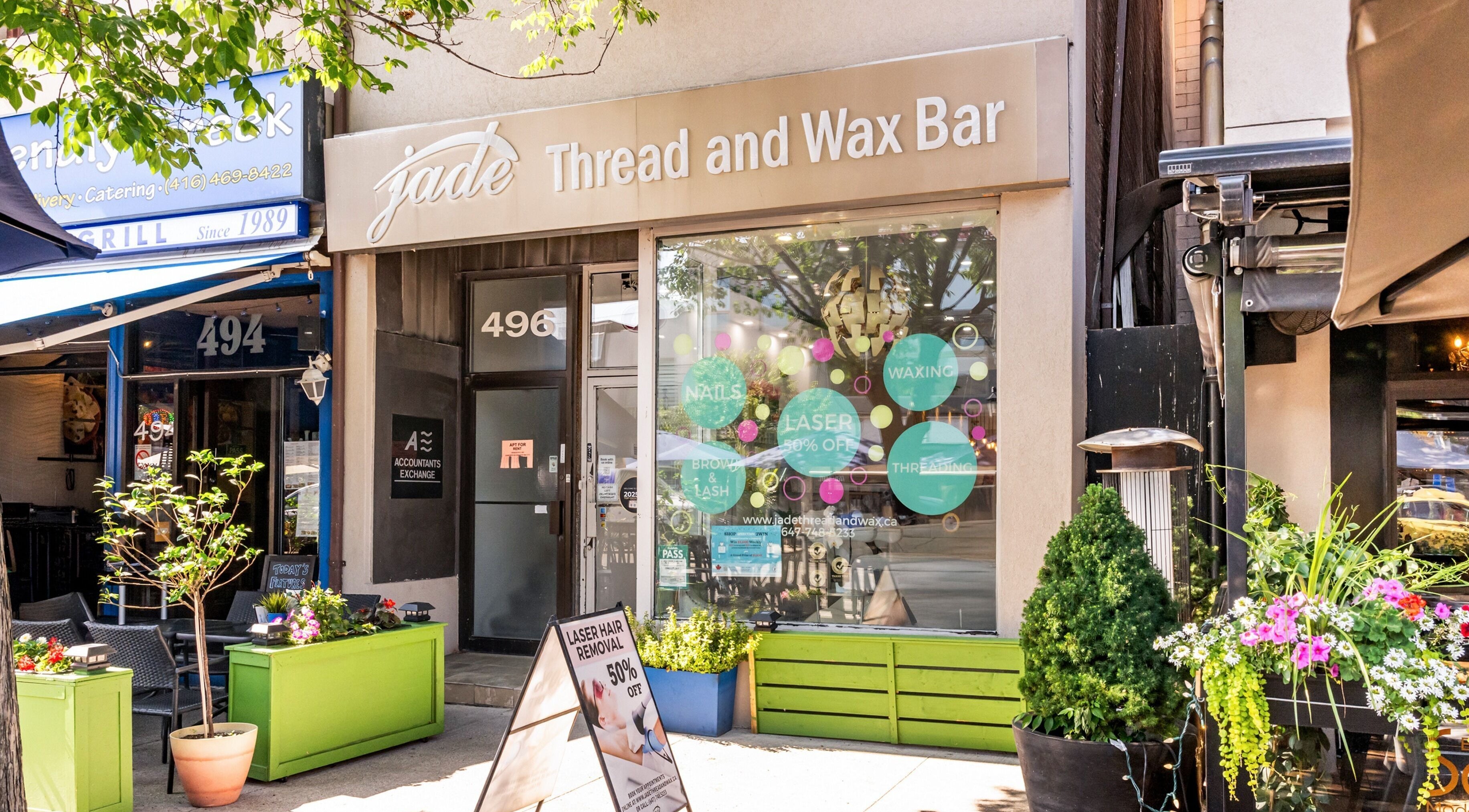 Front view of Jade Thread and Wax Bar - Danforth in Toronto, Ontario, CA with vibrant signage and plants.
