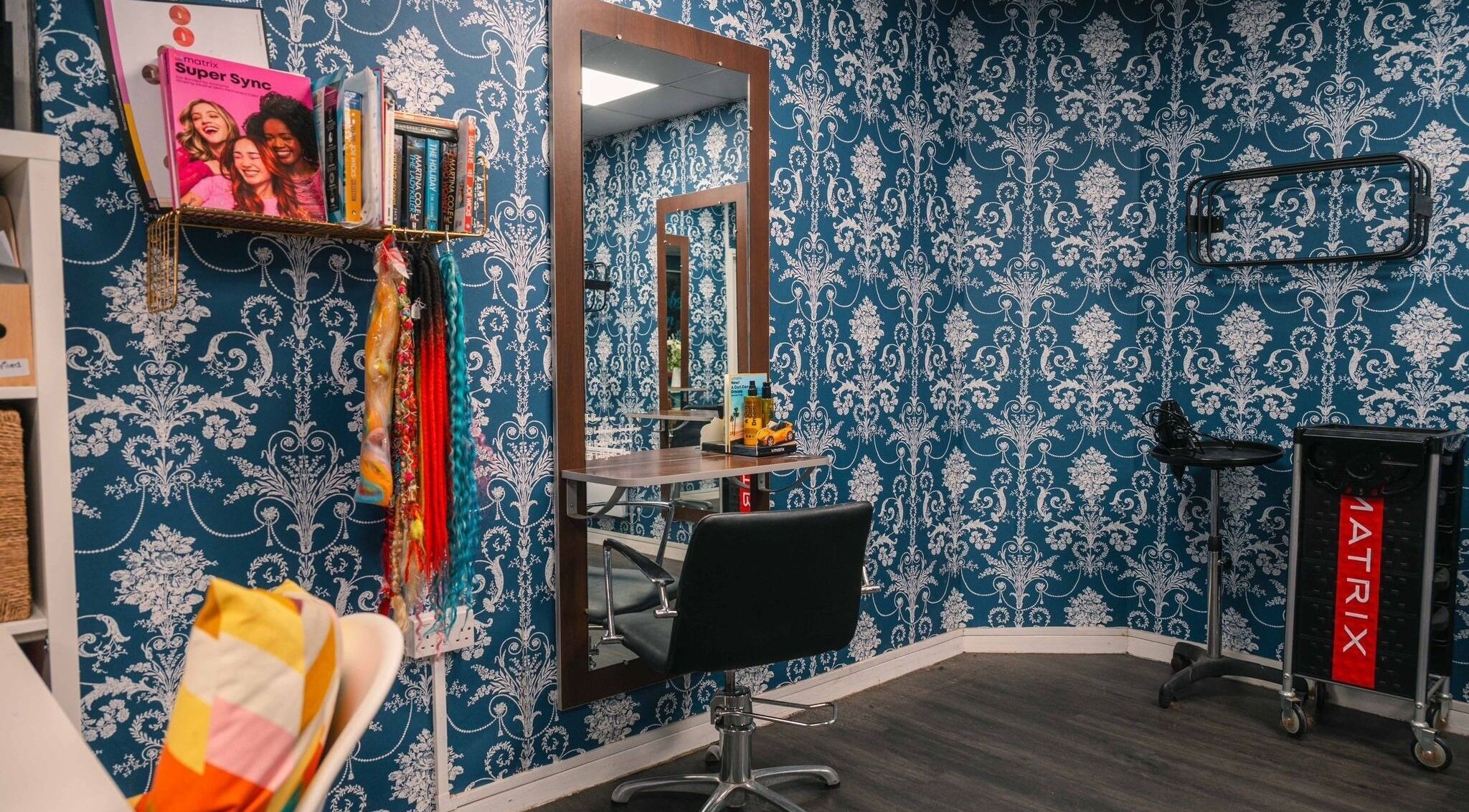 Chic styling station in Bobby Bob's Salon & Barber Shop, Halstead, England, GB with ornate blue wallpaper.
