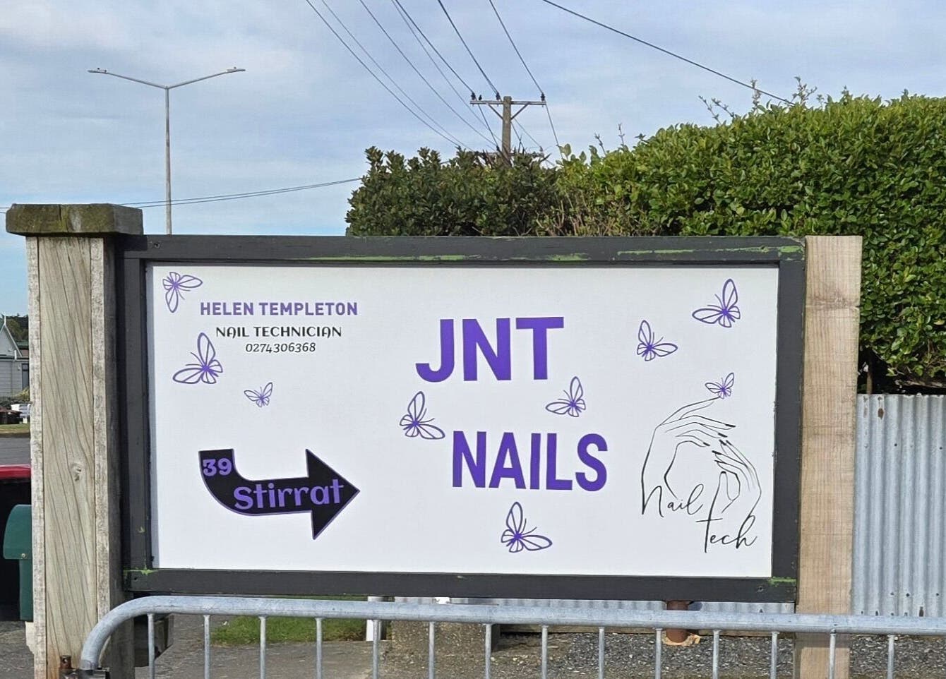Sign for JNT Nails in Invercargill, Southland, NZ, featuring butterflies and a nail tech contact.