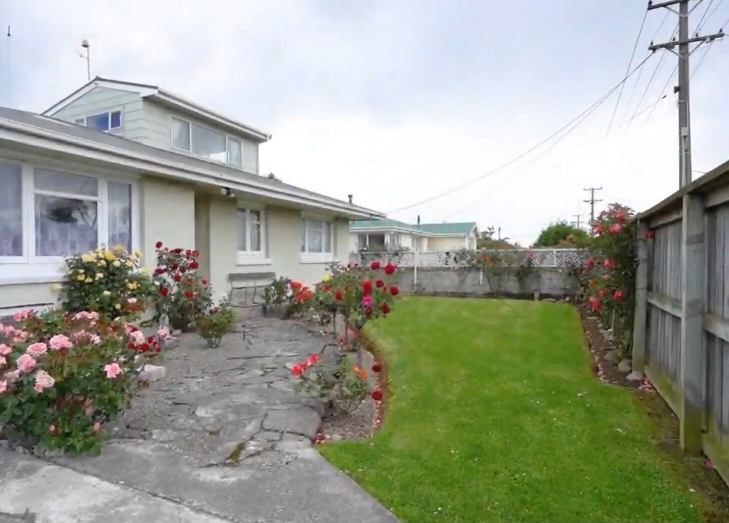 Charming garden facade at JNT Nails, Invercargill, Southland, NZ, with blooming roses and manicured lawn.