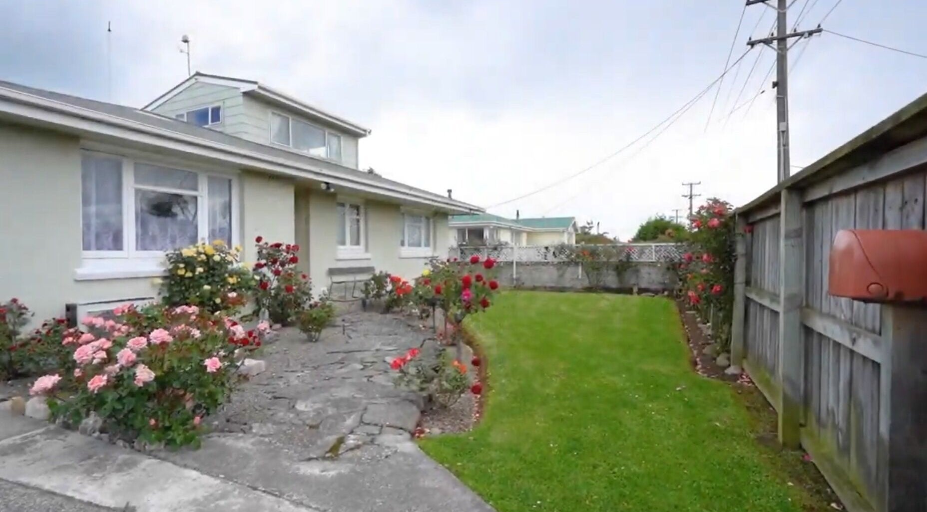 Charming garden facade at JNT Nails, Invercargill, Southland, NZ, with blooming roses and manicured lawn.