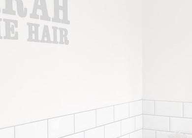 Interior corner at Sarah and the Hair, Durham, England, GB, featuring a minimalist mirror and tiled walls.