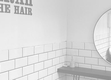 Modern interior of Sarah and the Hair salon in Durham, England, GB with white tiles and round mirror.