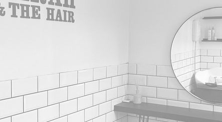Modern interior of Sarah and the Hair salon in Durham, England, GB with white tiles and round mirror.