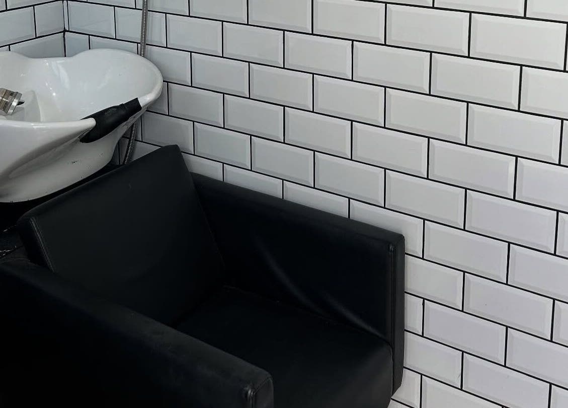 Modern wash station at Sarah and the Hair in Durham, England, GB with sleek black chair and tiled wall.