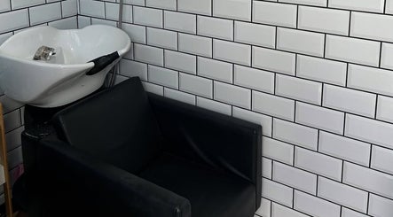 Modern wash station at Sarah and the Hair in Durham, England, GB with sleek black chair and tiled wall.