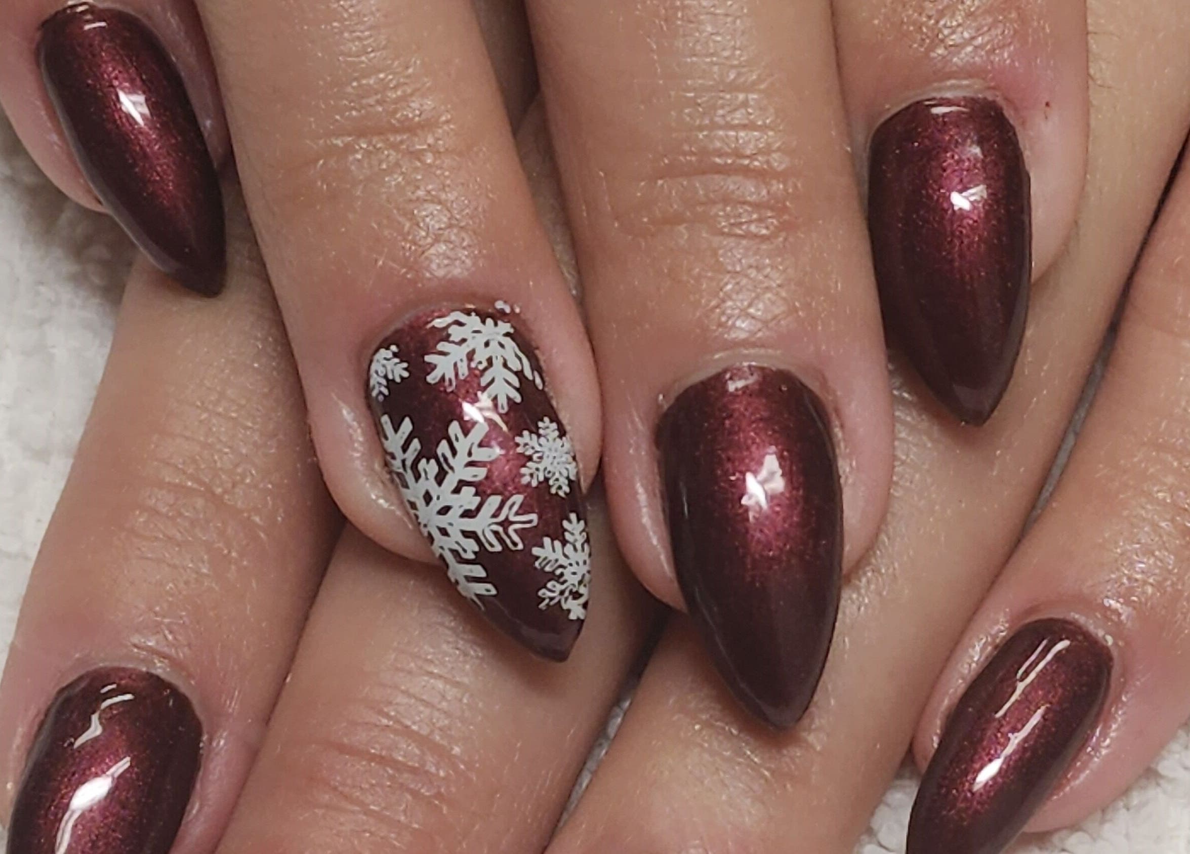 Burgundy nails with white snowflakes at Manifested Beauty, Rocky Mountain House, Alberta, CA.