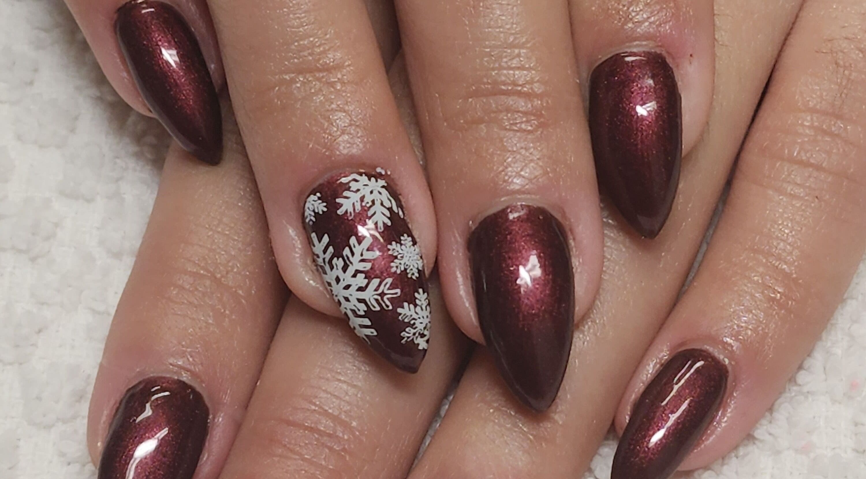 Burgundy nails with white snowflakes at Manifested Beauty, Rocky Mountain House, Alberta, CA.