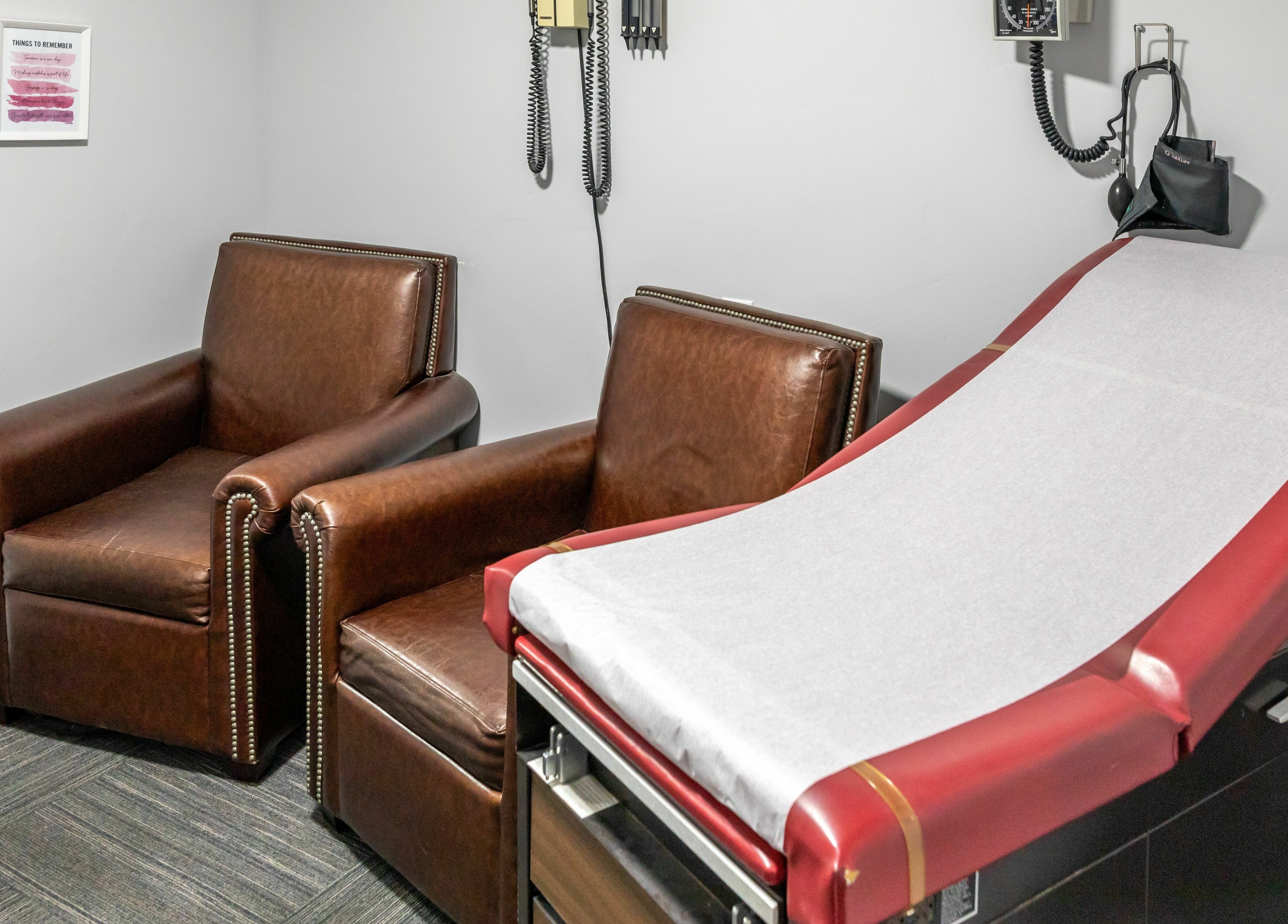 Cozy wellness treatment room at Health and Vitality in Orem, Utah, US, featuring leather chairs and a treatment table.