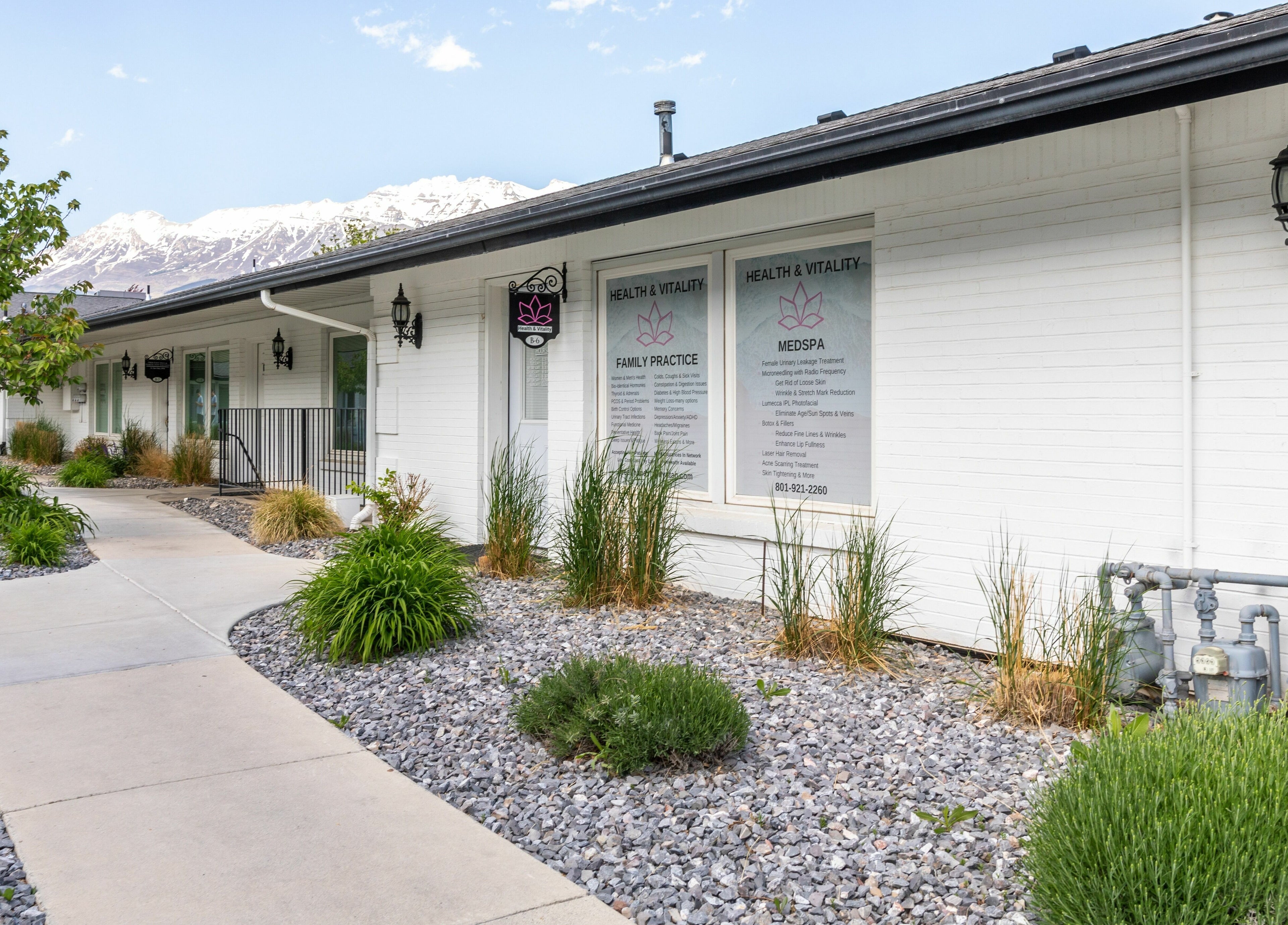 Entrance of Health and Vitality in Orem, Utah, US featuring a landscaped pathway with mountains in the background.