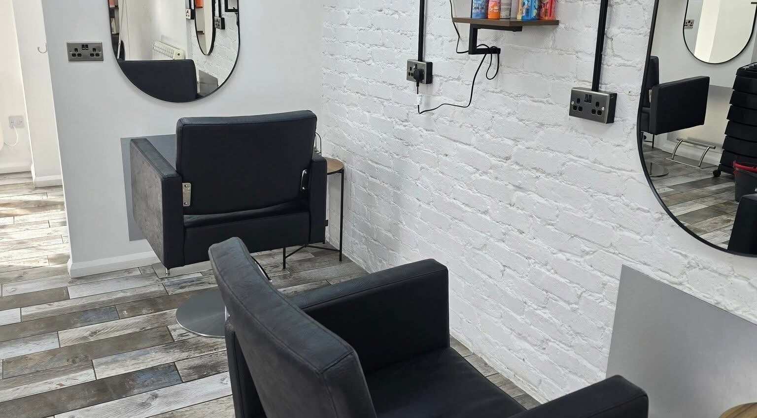 Modern salon seating at Liv Bridal & Hair in Camborne, England, GB, featuring sleek black chairs and round mirrors.