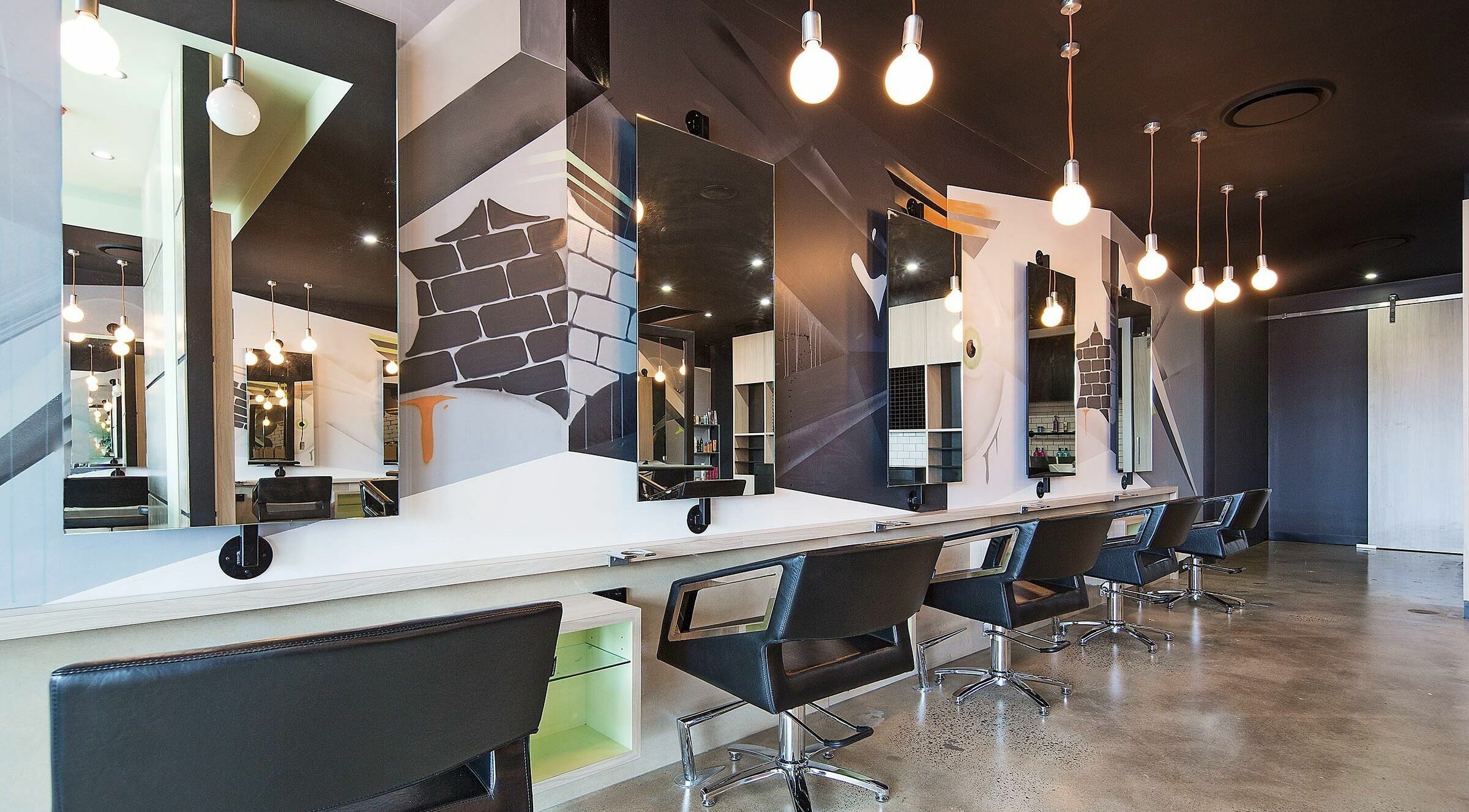 Modern salon interior of Lunatic Fringe in Clayfield, Queensland, AU with stylish chairs and artistic mirrors.