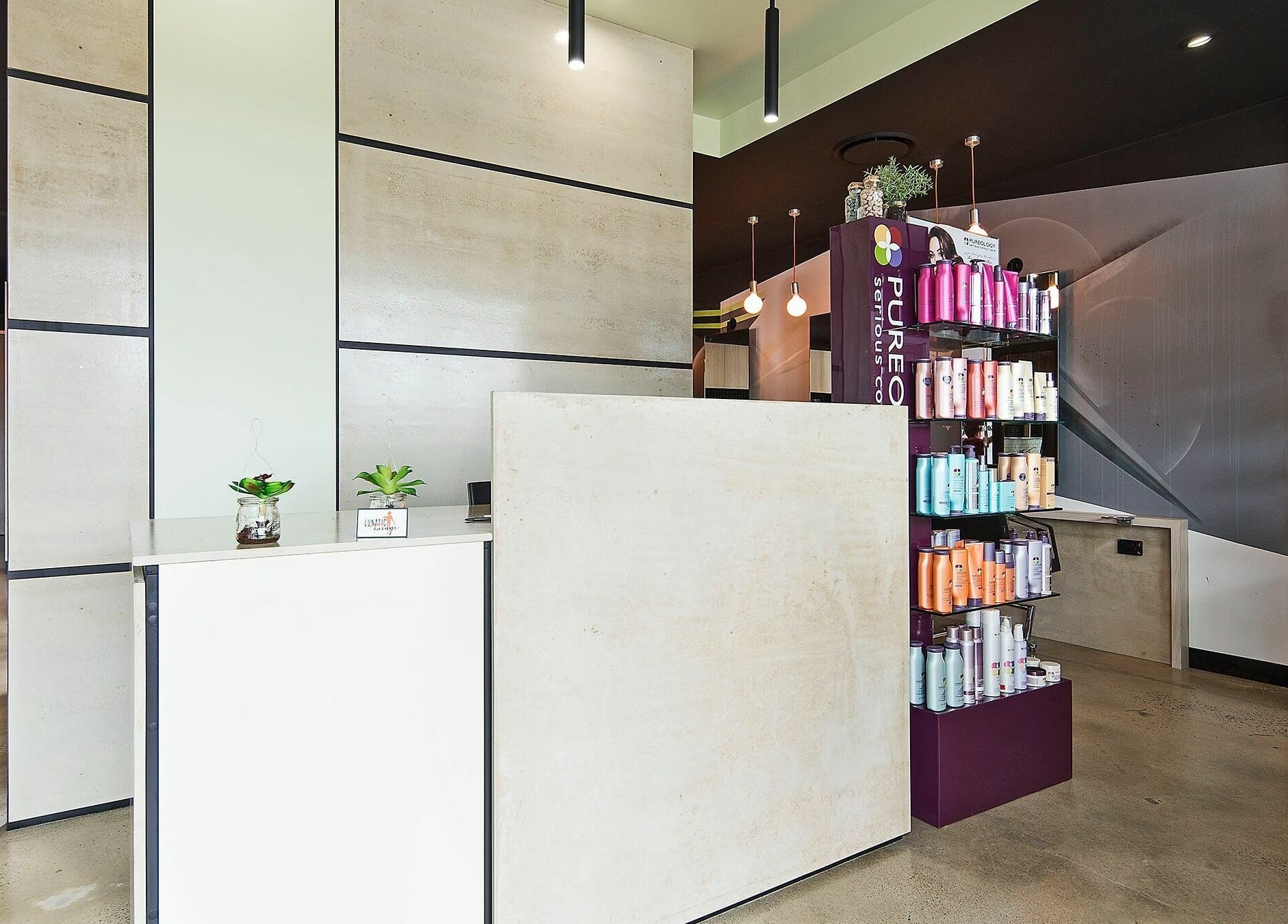 Reception area of Lunatic Fringe in Clayfield, Queensland, AU with modern decor and beauty product display.