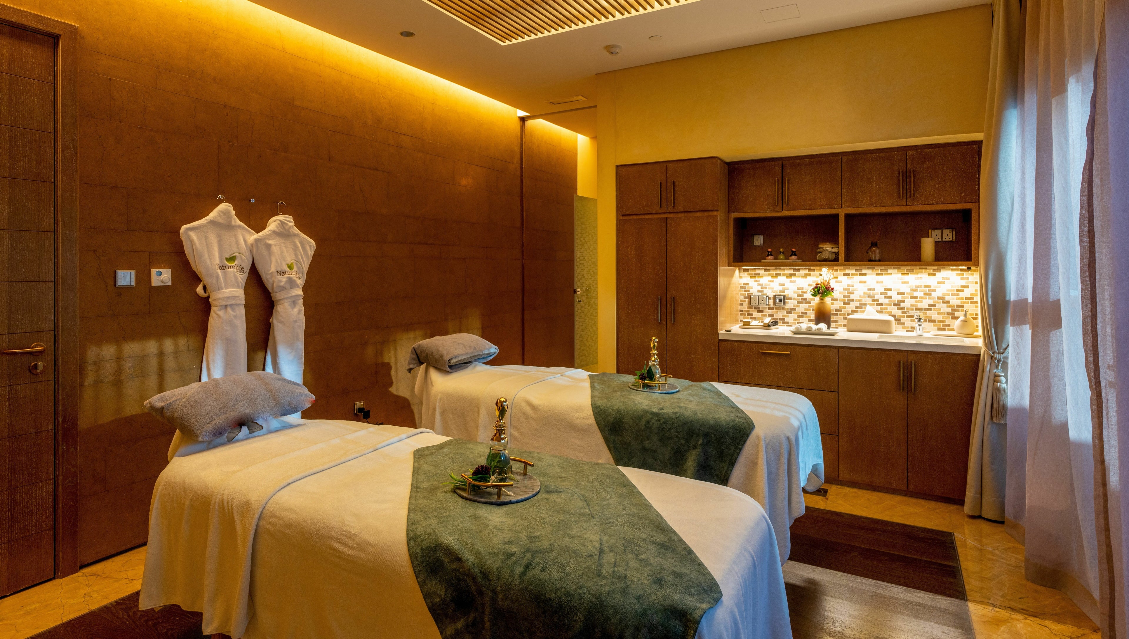 Relaxing treatment room at Naturelife Spa Rixos Marina Abu Dhabi, featuring twin massage tables. Abu Dhabi, AE.