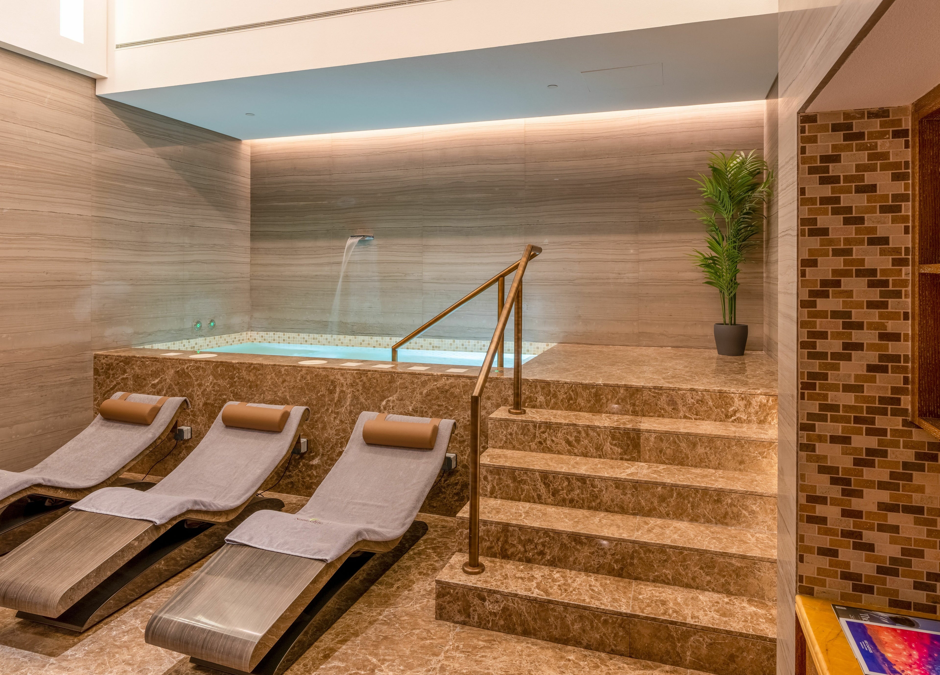Luxurious spa interior at Naturelife Spa Rixos Marina Abu Dhabi featuring elegant loungers and a tranquil jacuzzi.