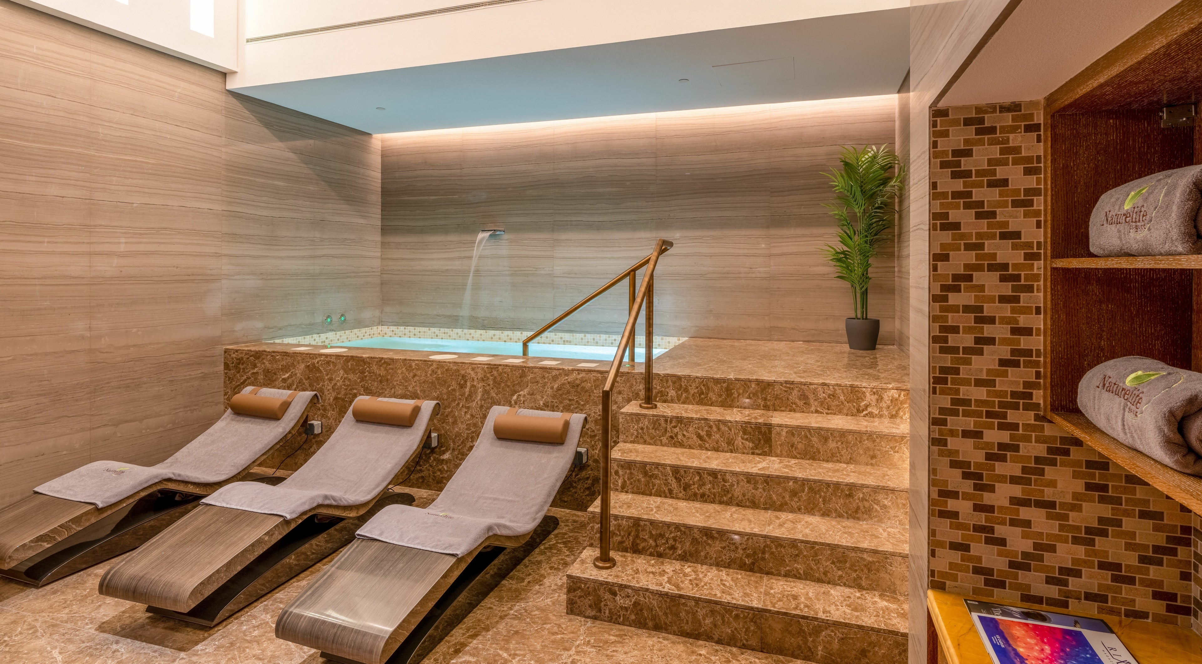 Luxurious spa interior at Naturelife Spa Rixos Marina Abu Dhabi featuring elegant loungers and a tranquil jacuzzi.