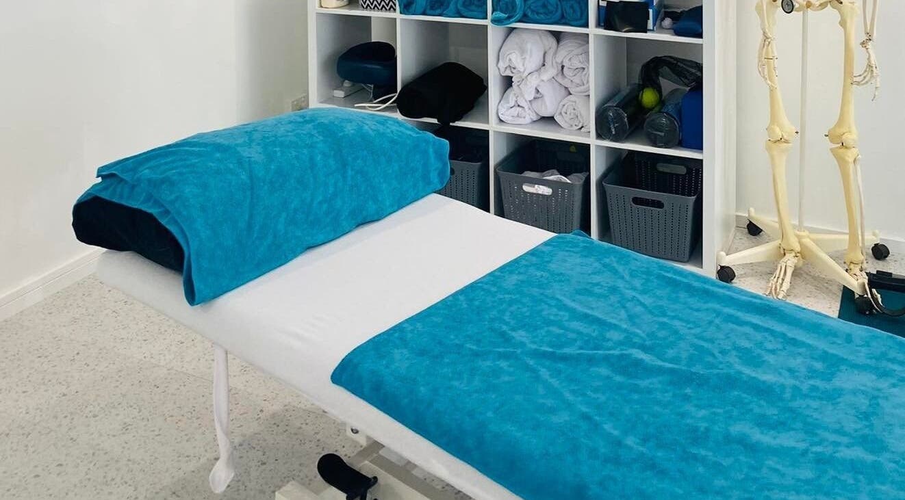 Therapy bed at Yogio Physio and Yoga Therapy in PALM COVE, Queensland, AU with folded towels and a skeleton model.