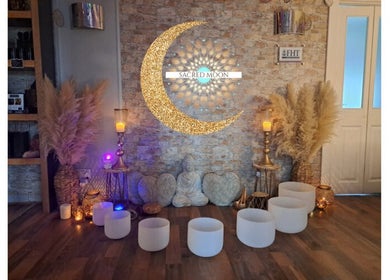 Cozy meditation space at Sacred Moon Wellbeing in Horbury, England, featuring candles and a golden crescent moon.