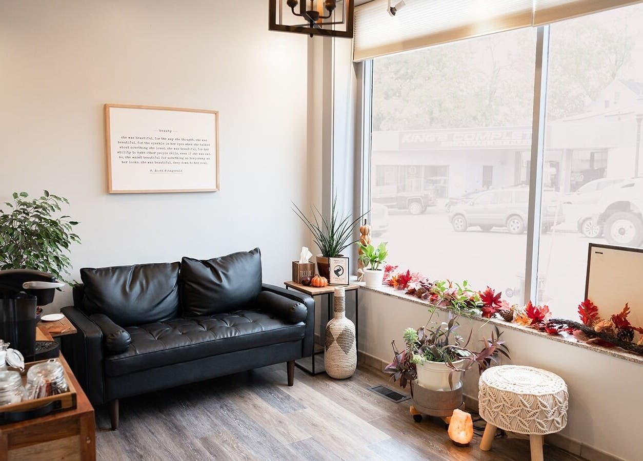 Relaxing lounge area in Expressions Hair Studio, Reading, Massachusetts, US, with a black sofa and decor.