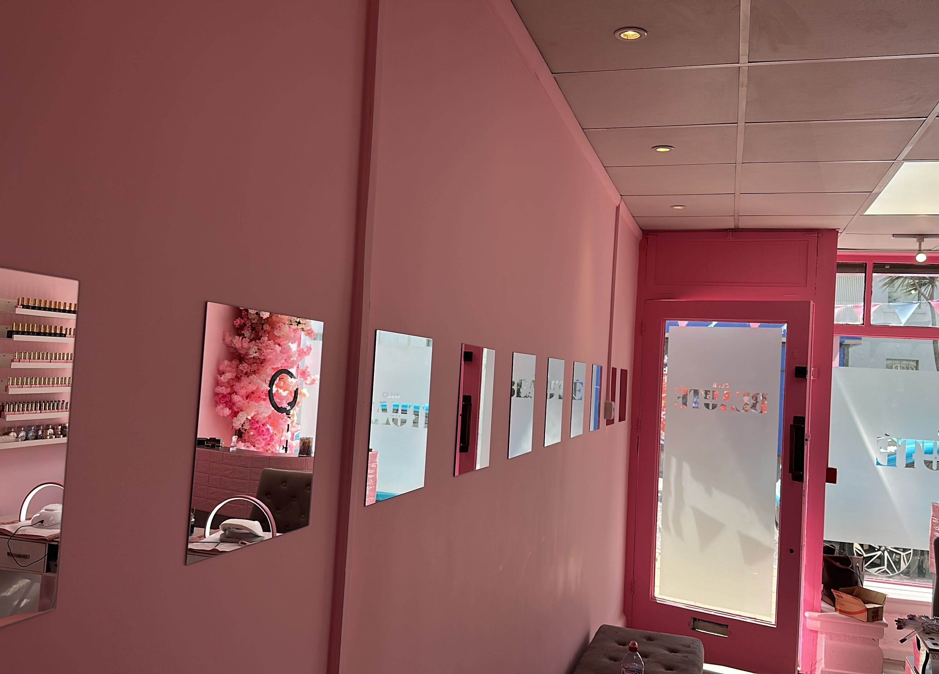 Chic pink interior of Club Beauté in Lee-on-the-Solent, England, GB with stylish mirrors and nail care setup.