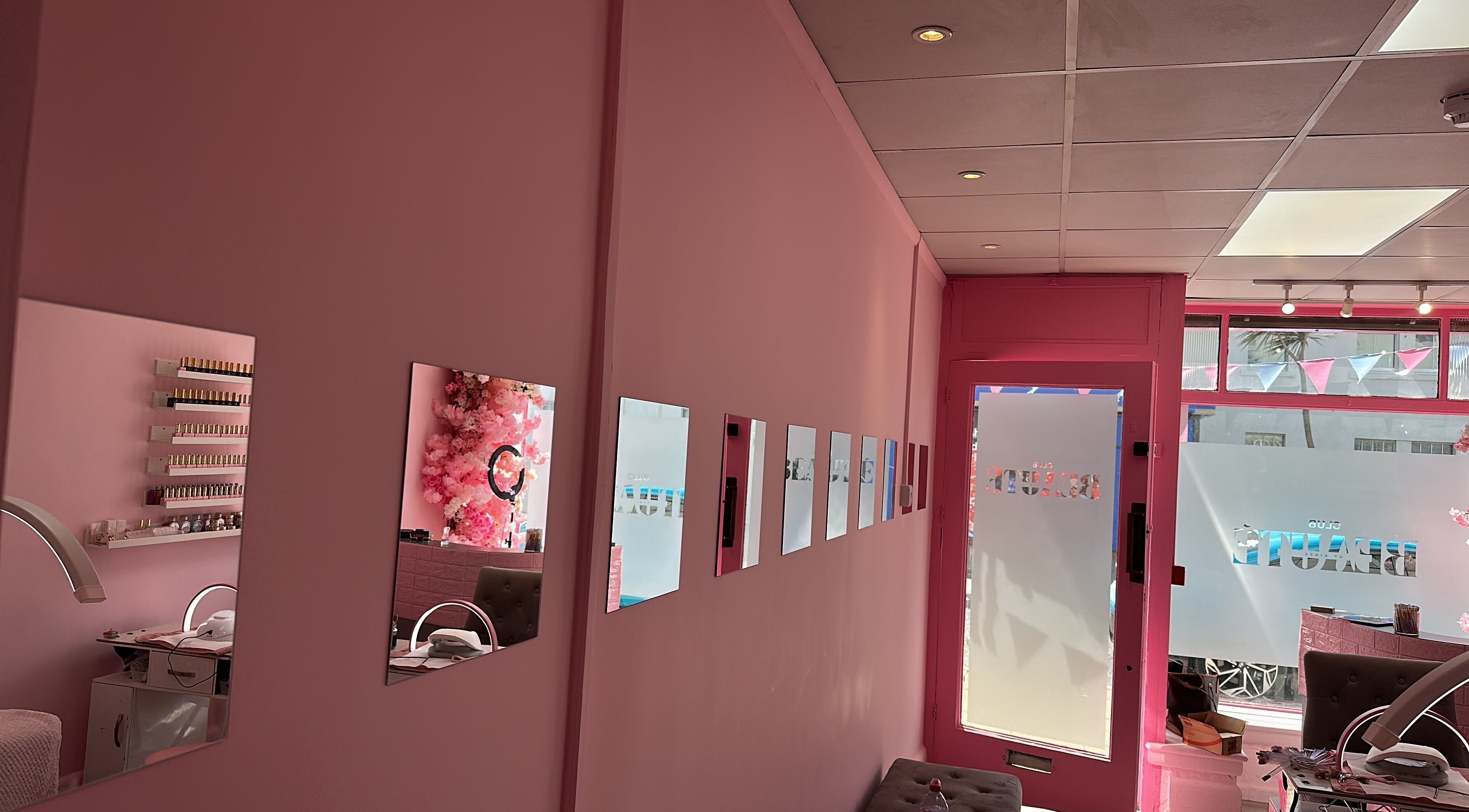 Chic pink interior of Club Beauté in Lee-on-the-Solent, England, GB with stylish mirrors and nail care setup.