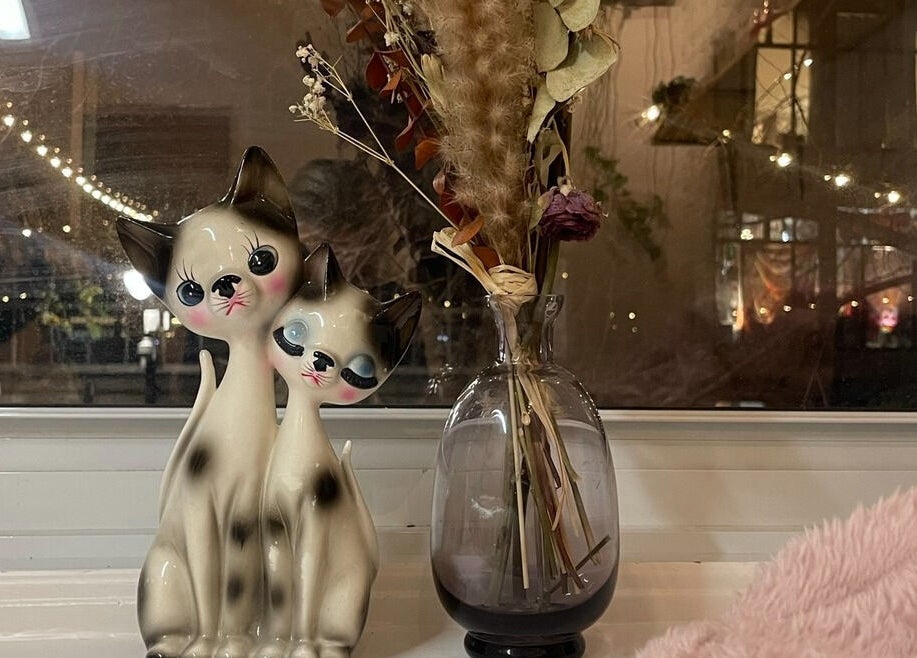 Whimsical ceramic cats by a vase at Lehita Lashes Artistry, Montréal, Québec, CA, creating a cozy ambiance.