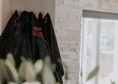 Salon capes hanging in Halam Salon, Newark, England, GB with stone wall and modern decor.