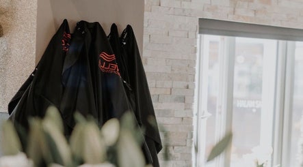 Salon capes hanging in Halam Salon, Newark, England, GB with stone wall and modern decor.