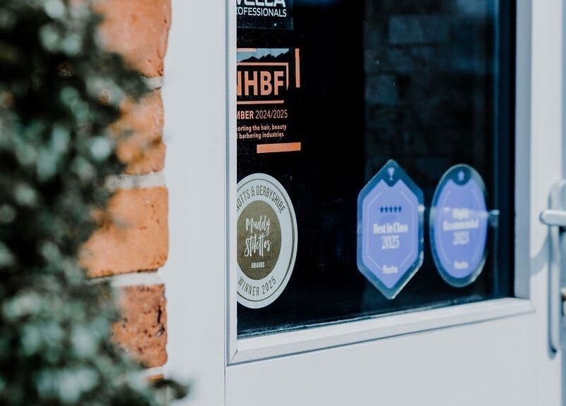 Close-up of award stickers on Halam Salon door at Newark, England, GB, celebrating excellence in beauty and wellness.