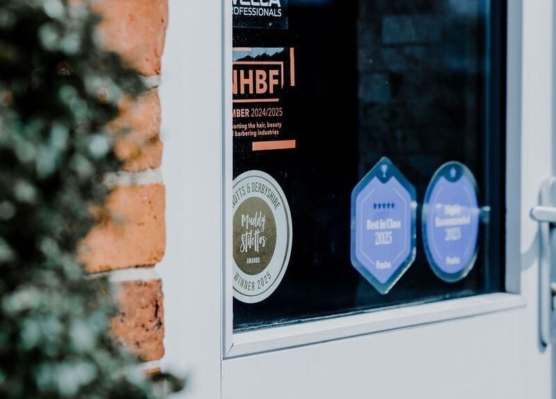 Close-up of award stickers on Halam Salon door at Newark, England, GB, celebrating excellence in beauty and wellness.