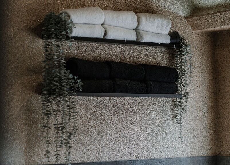 Luxe black and white towels on a wall at Halam Salon, Newark, England, GB, elegantly adorned with greenery.