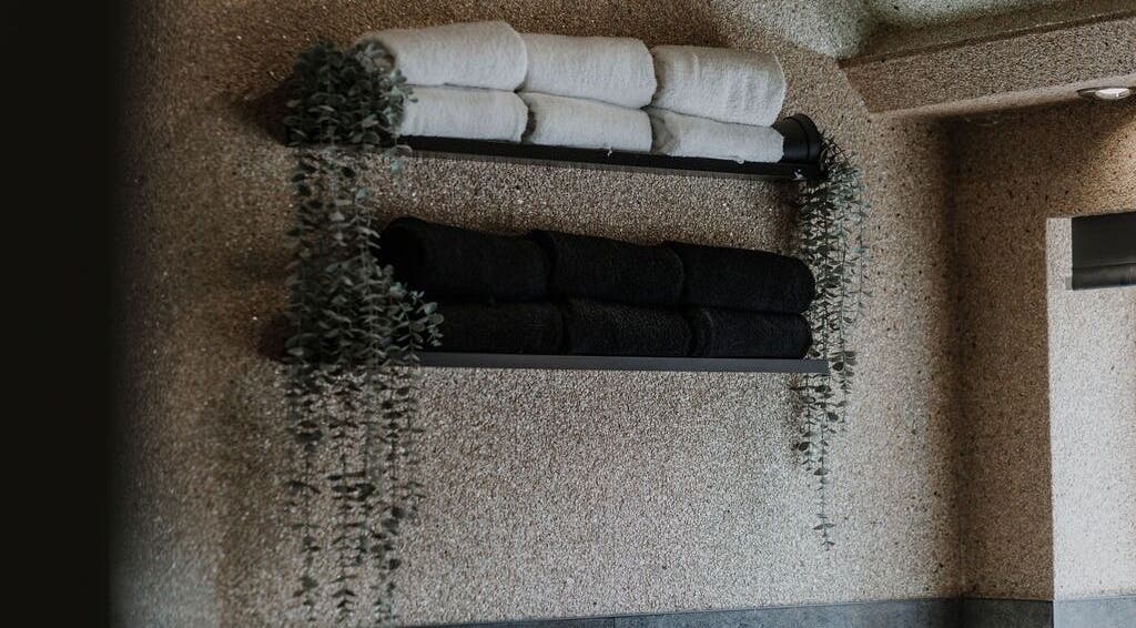 Luxe black and white towels on a wall at Halam Salon, Newark, England, GB, elegantly adorned with greenery.