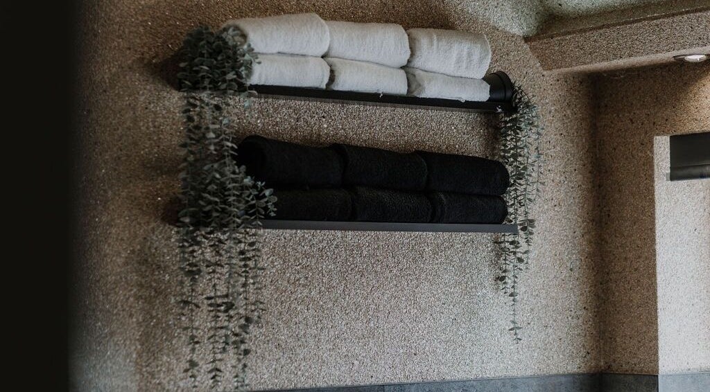Luxe black and white towels on a wall at Halam Salon, Newark, England, GB, elegantly adorned with greenery.