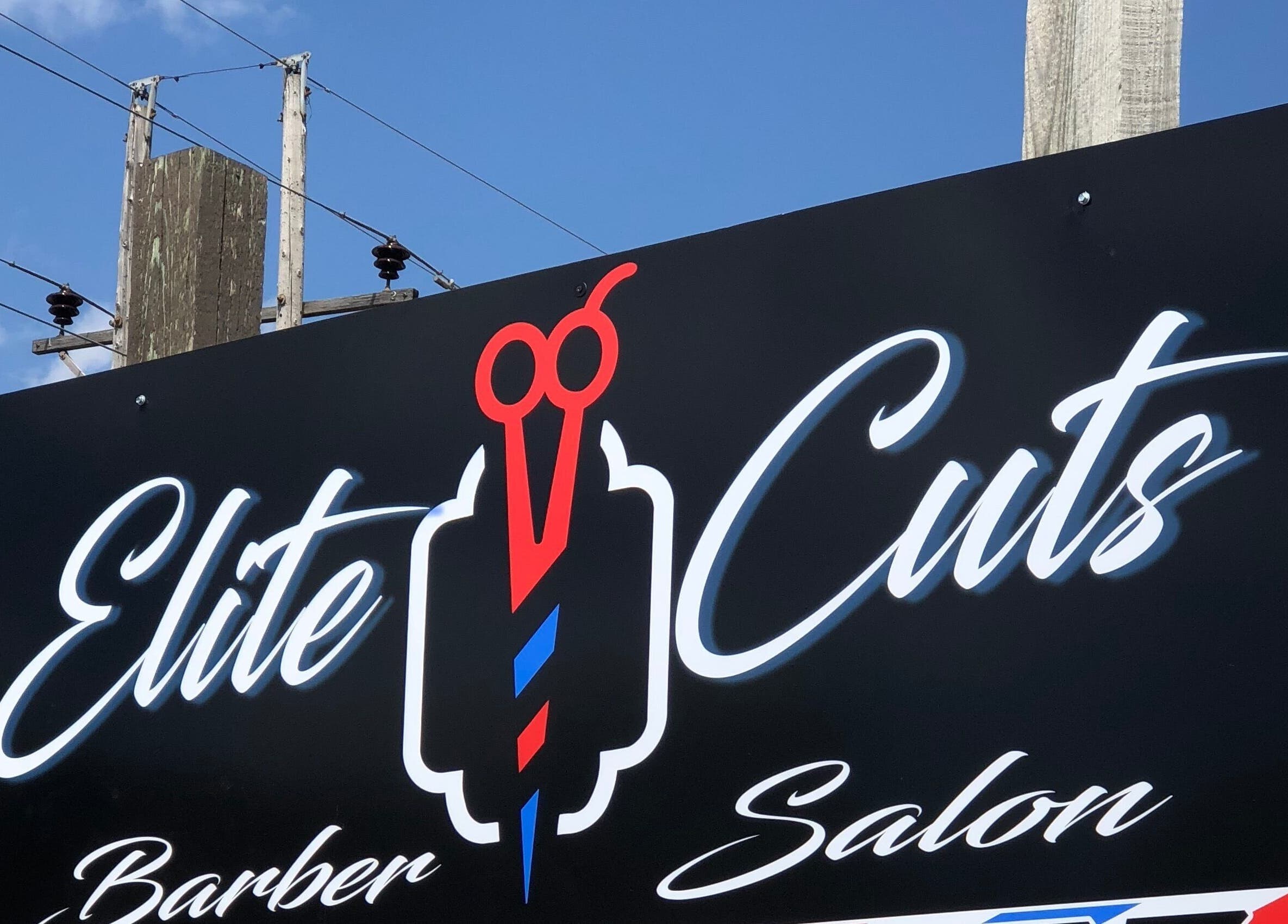Elite Cuts Barber Salon sign at Chippewa Falls, Wisconsin, US under a clear blue sky.