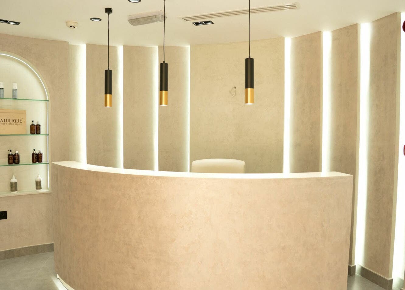 Elegant reception area at Royal Nordic Beauty Salon, Dubai, AE with sleek shelves and pendant lights.