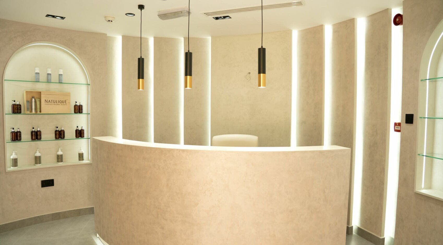 Elegant reception area at Royal Nordic Beauty Salon, Dubai, AE with sleek shelves and pendant lights.