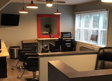 Stylish interior of Gents Barber Shop in Hampton, New Hampshire, US featuring modern chairs and a large mirror.