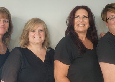 Team of stylists at Gents Barber Shop in Hampton, New Hampshire, US, posing and smiling together.