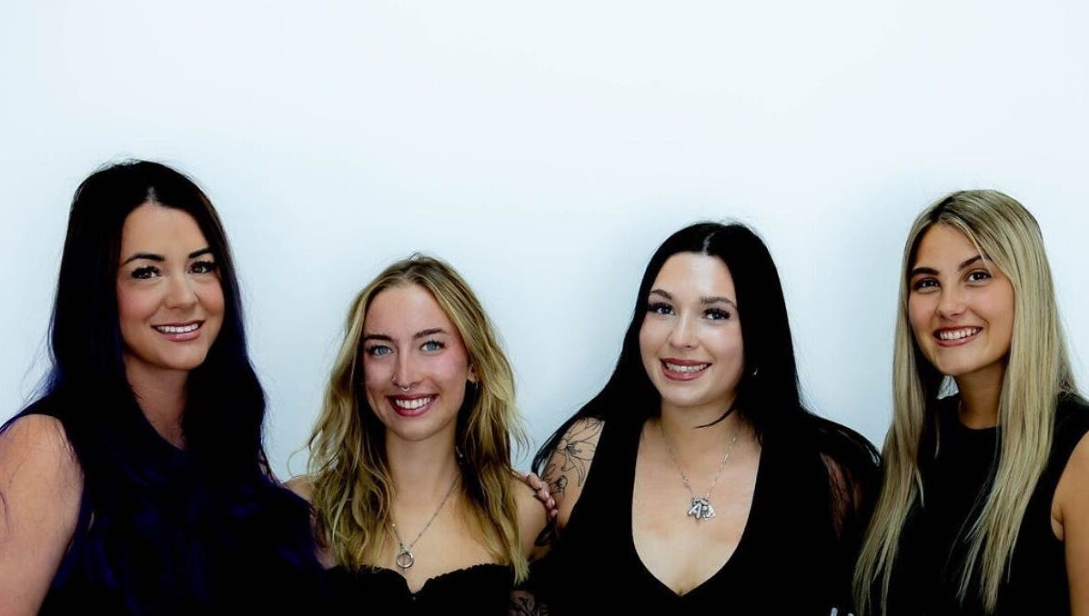 Team of stylists at D's Lashes & Esthetics in Spruce Grove, Alberta, CA, smiling against a white background.