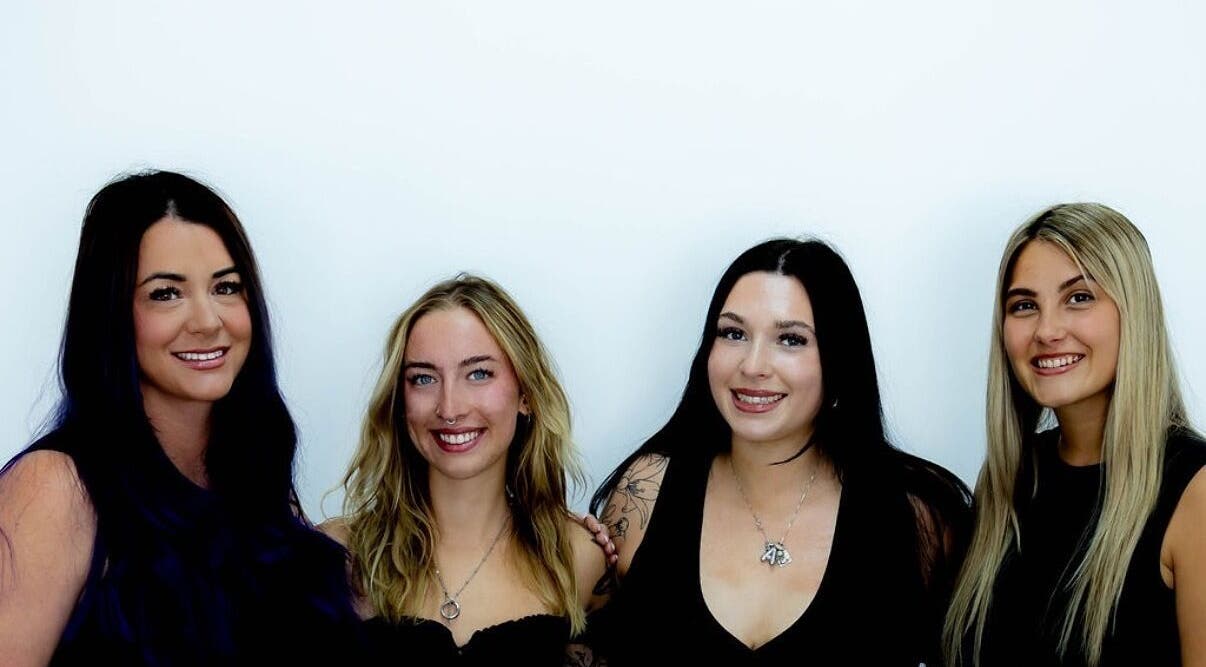 Team of stylists at D's Lashes & Esthetics in Spruce Grove, Alberta, CA, smiling against a white background.