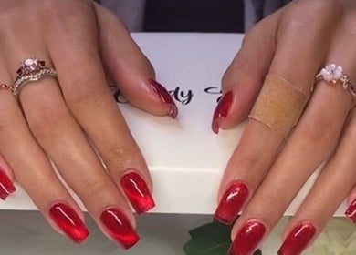 Elegant red manicured nails with rings at Eye Candy Esthetics By Shanai, Oshawa, Ontario, CA.