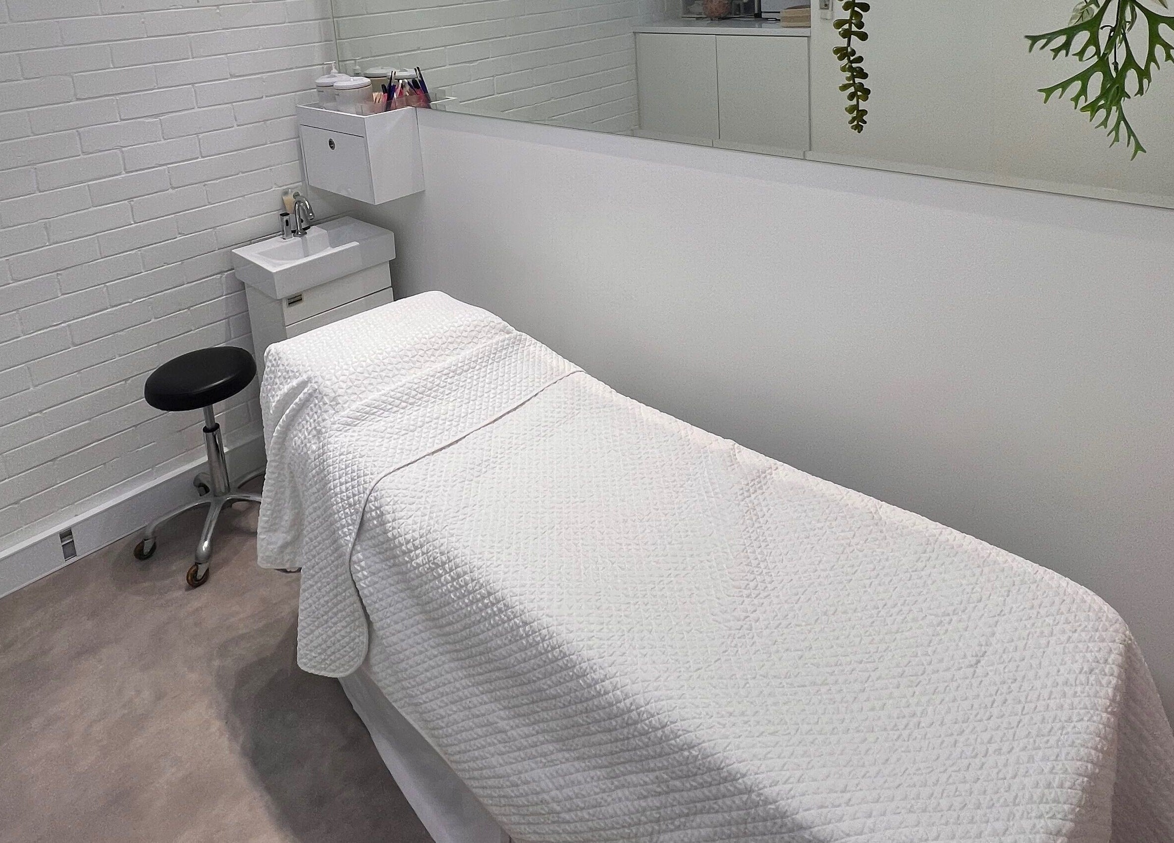 A serene treatment room at The Skin Genesis Collective in Nedlands, Western Australia, AU, showcasing a massage bed.