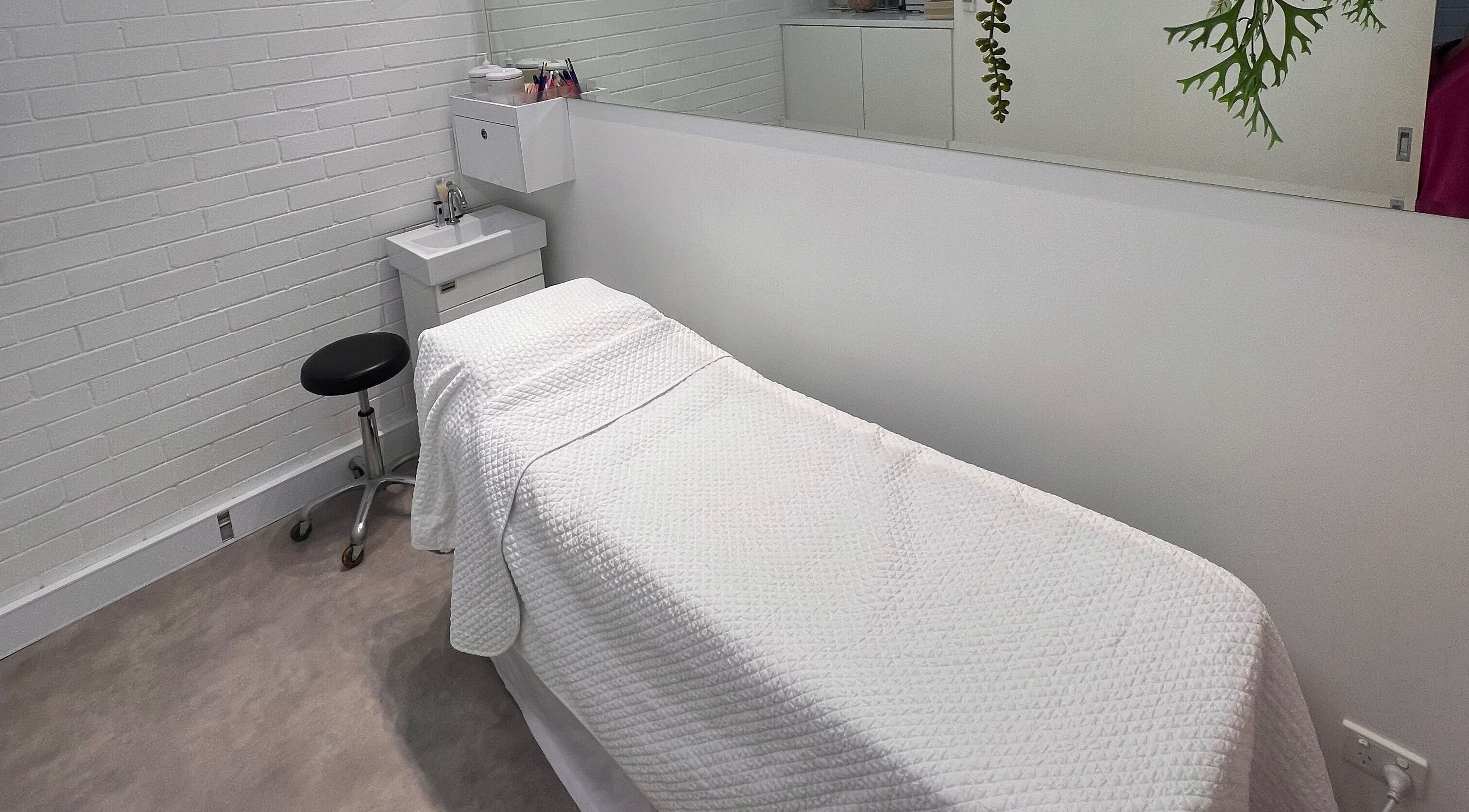 A serene treatment room at The Skin Genesis Collective in Nedlands, Western Australia, AU, showcasing a massage bed.