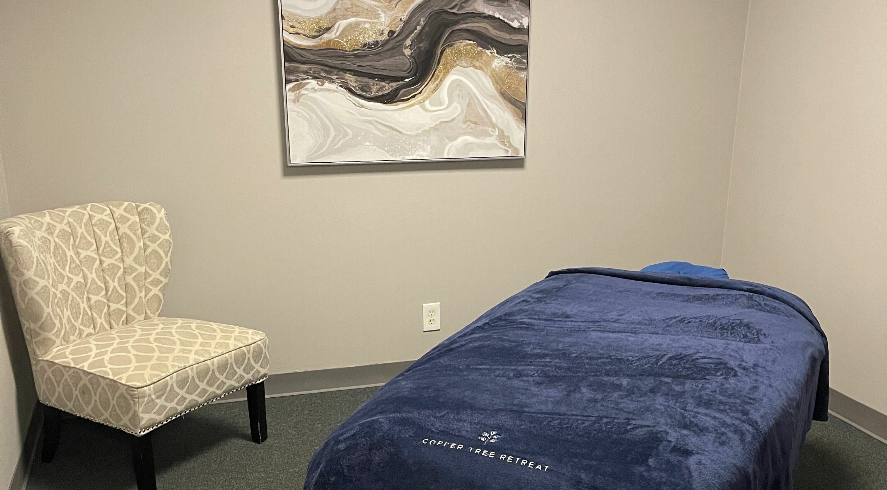Relaxing massage room at Copper Tree Retreat, Longview, Texas, US, featuring cozy chair and elegant artwork.