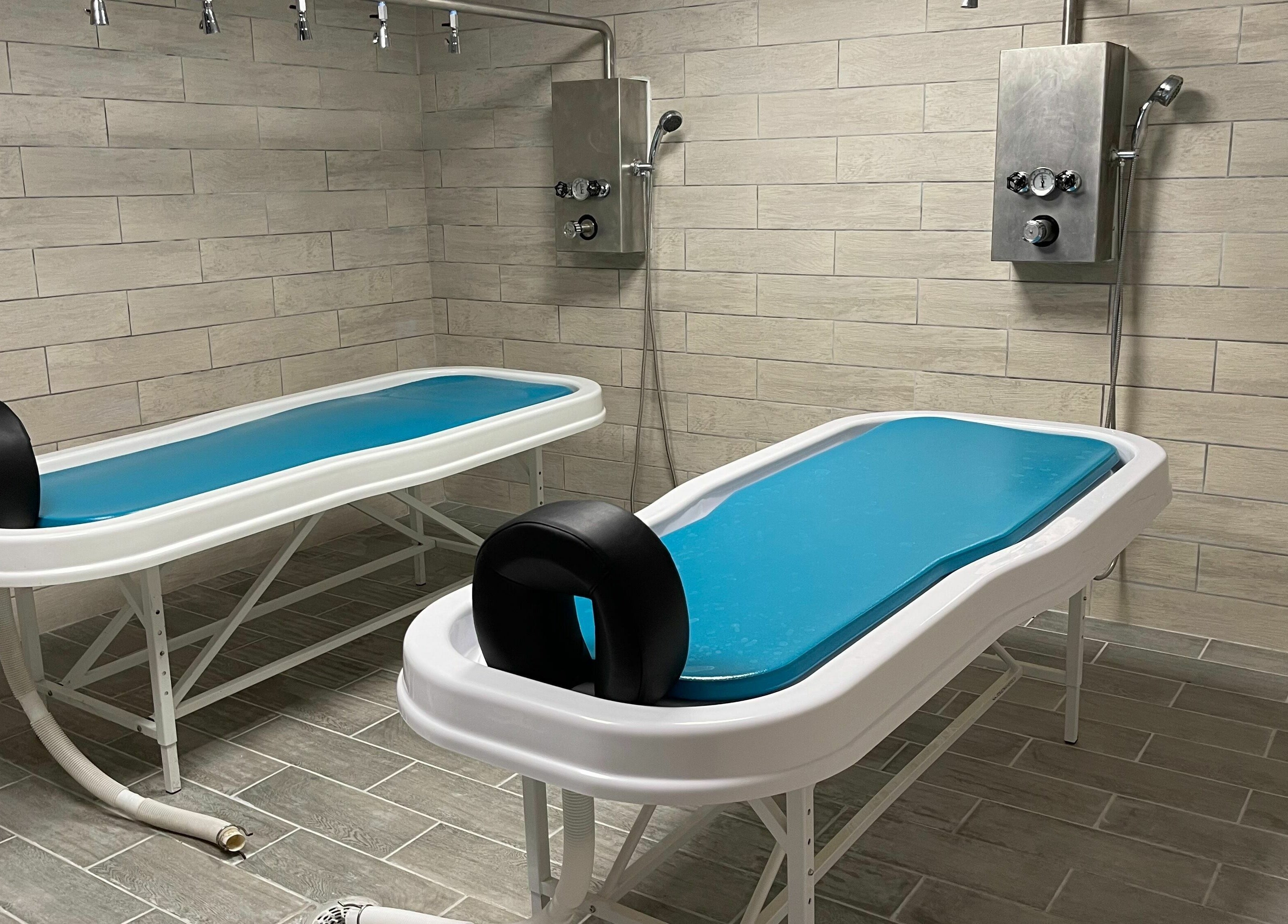 Modern spa treatment room at Copper Tree Retreat in Longview, Texas, US, featuring two sleek massage tables.