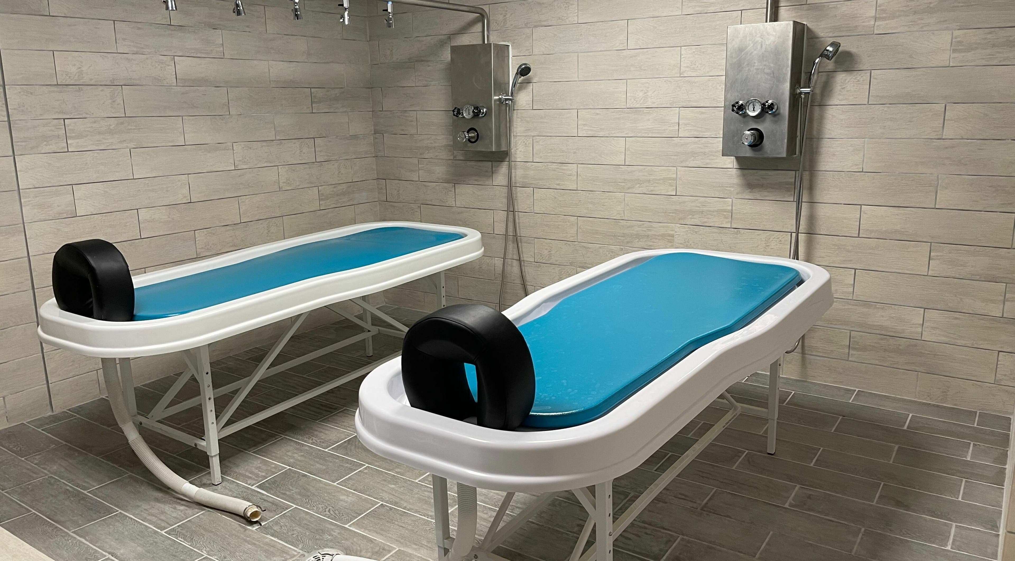 Modern spa treatment room at Copper Tree Retreat in Longview, Texas, US, featuring two sleek massage tables.